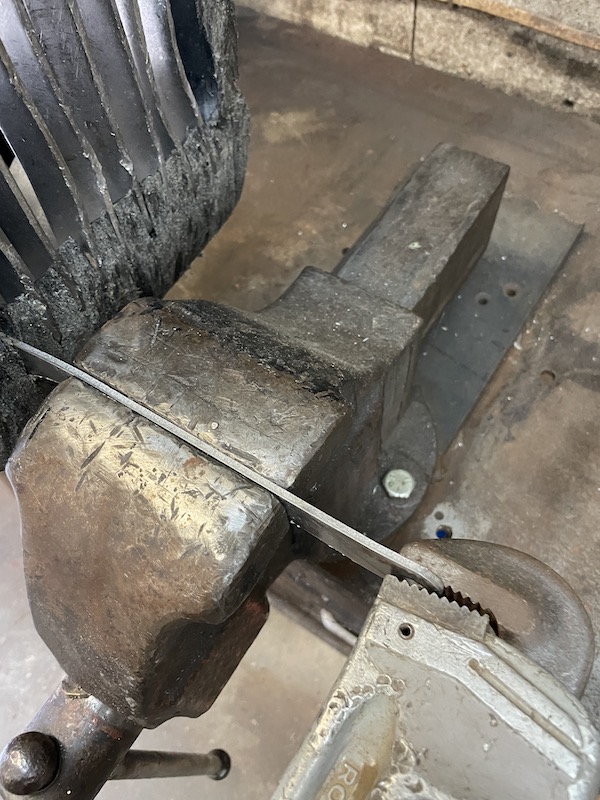 Outboard jet intake grate bar clamped in a vise with a pipe wrench used for straightening