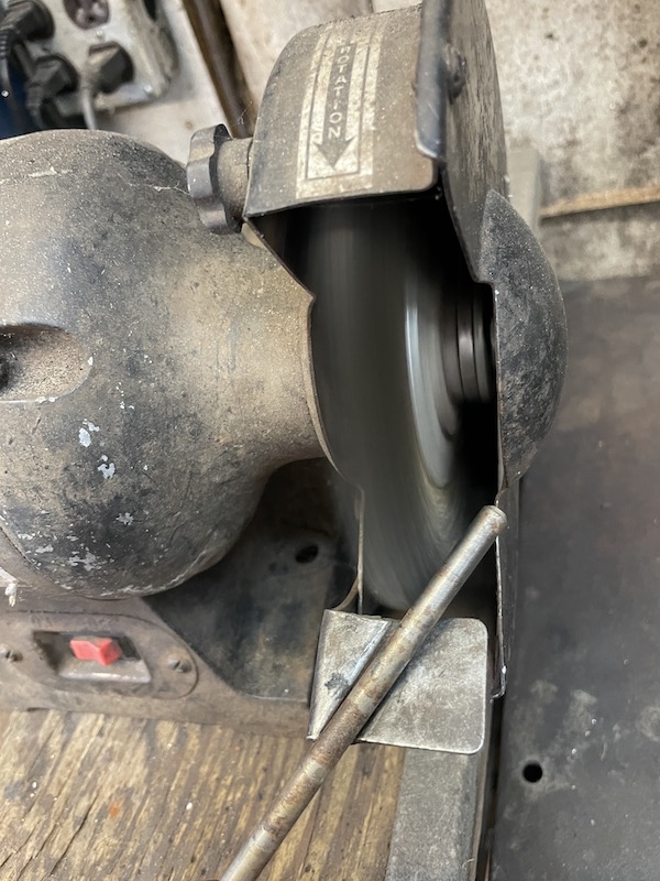 Outboard jet intake rod being cleaned on a wire wheel
